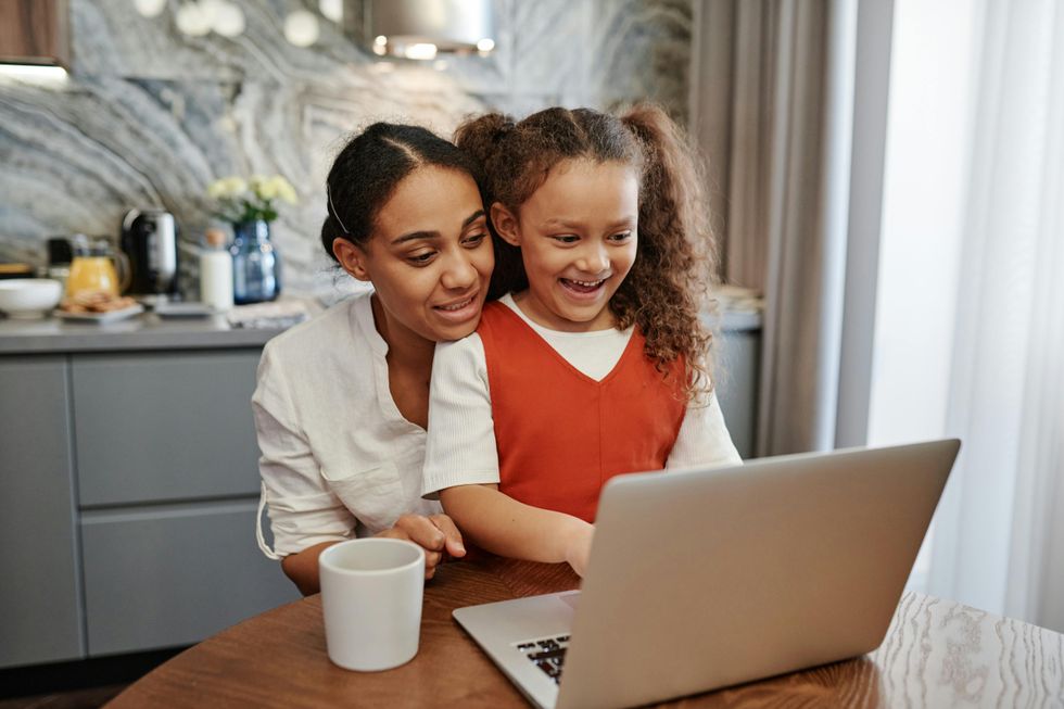 Mom and daughter using laptop at the kitchen table