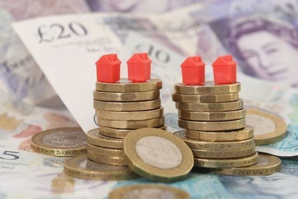 Monopoly pieces stacked on pound coins and notes