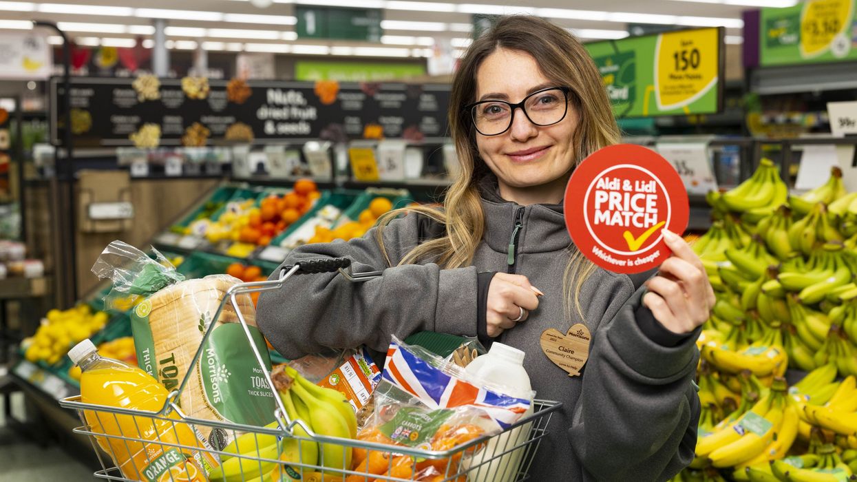 Morrisons employee holds basket of shopping and Aldi and Lidl price match guarantee