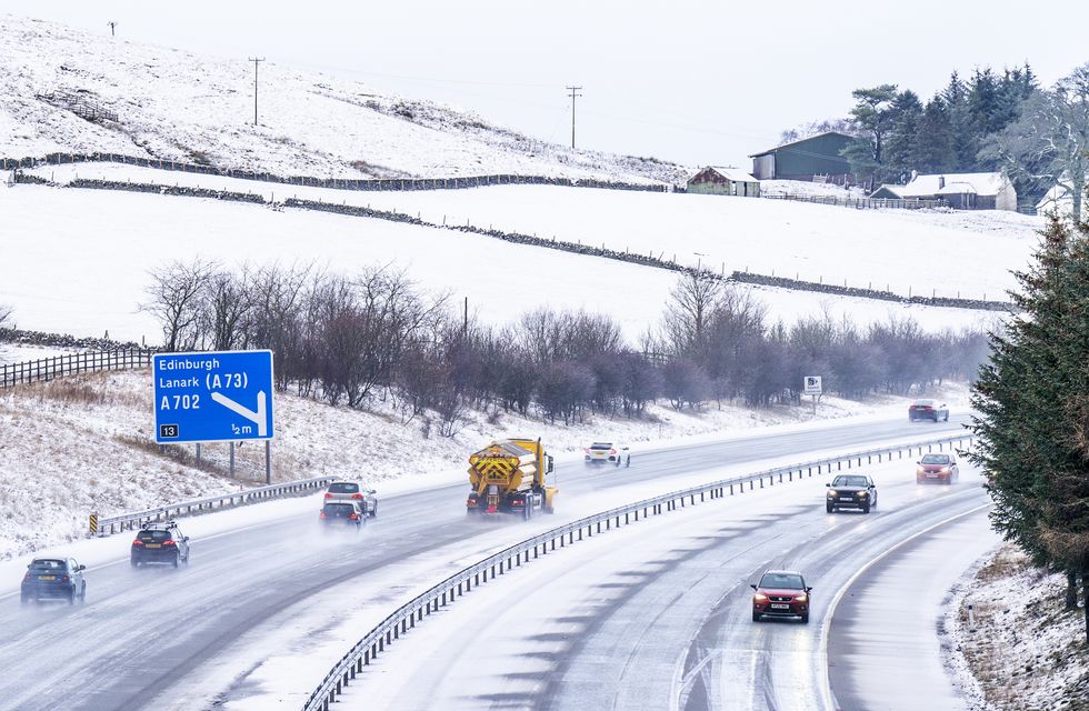 Motorists driving along a snowy and icy M8 motorway