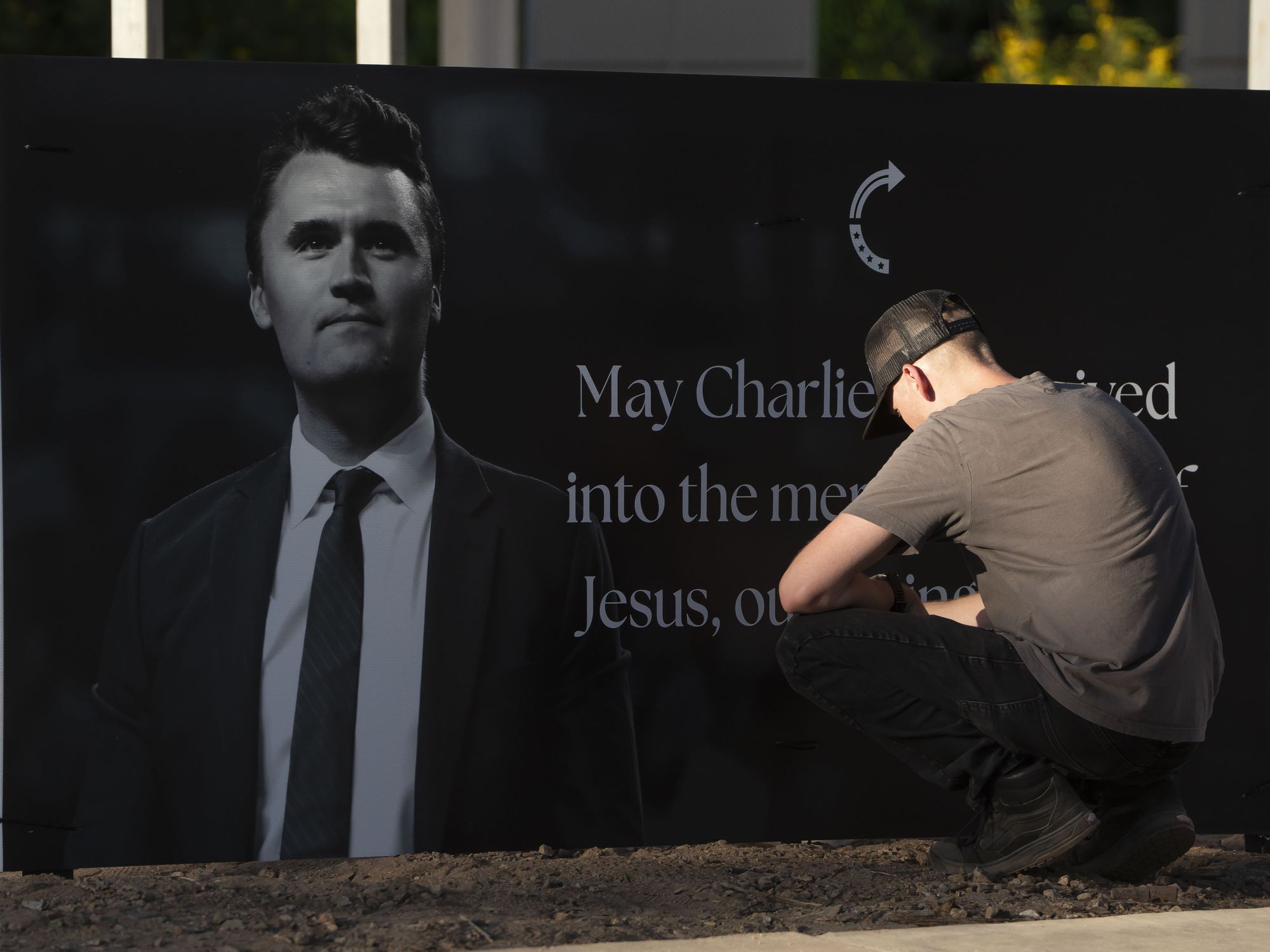 Mourner kneeling in front of a tribute to Charlie Kirk