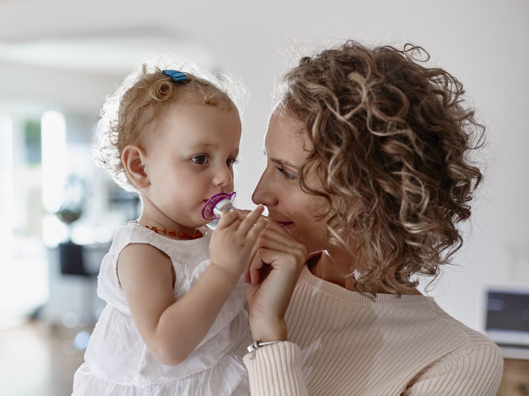 Mum holding baby who is using a pacifier