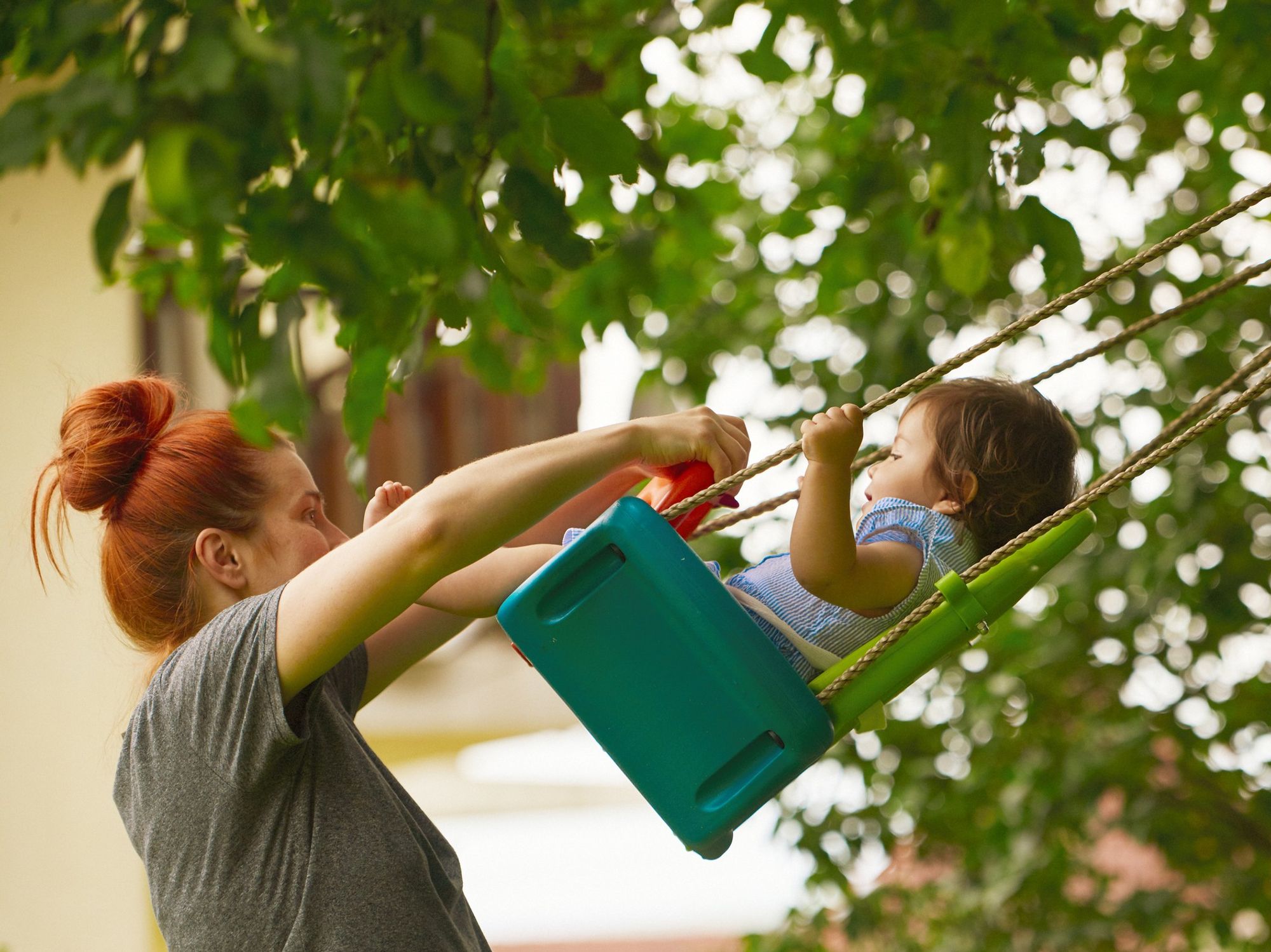 Mum pushing baby on swing