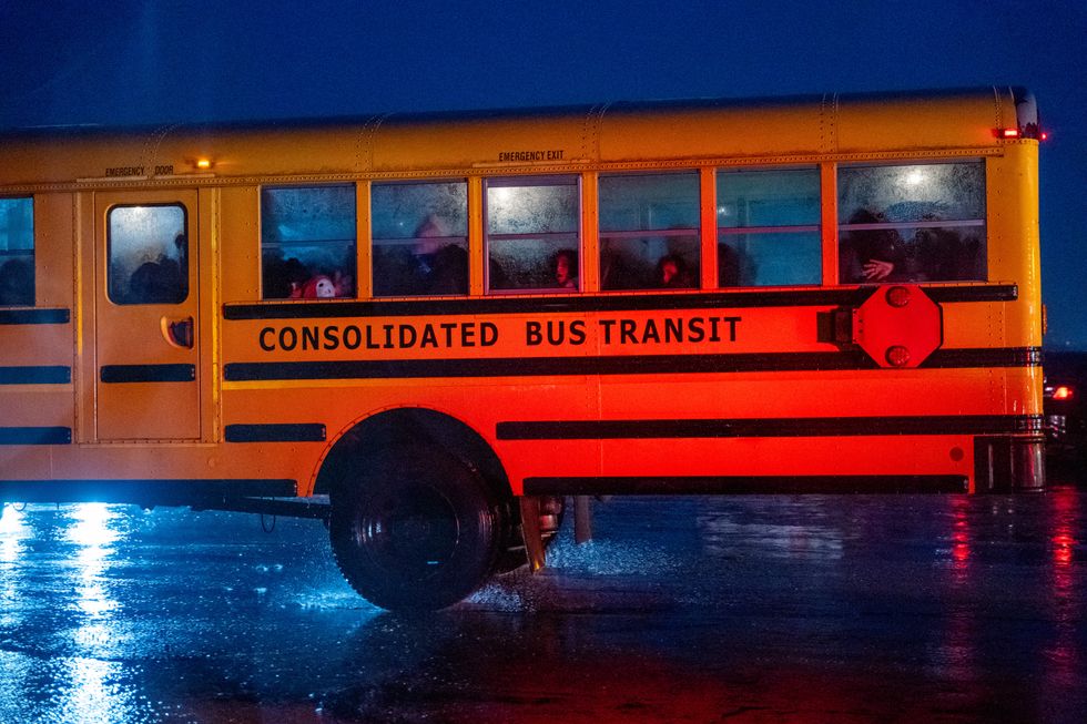 Nearly 2,000 migrants are evacuated by school buses from tents at Floyd Bennett Field to a local high school in preparation for a storm