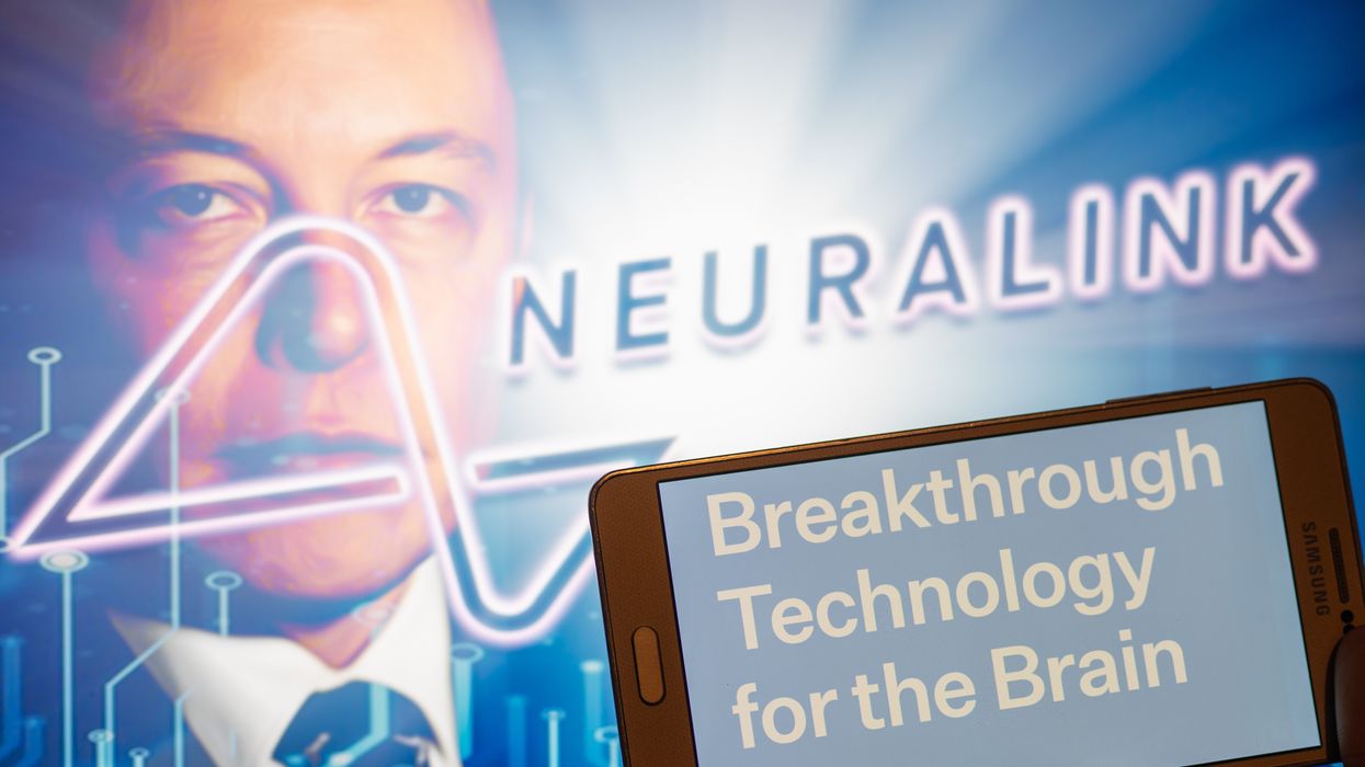 Neuralink logo displayed on mobile with founder Elon Musk seen on screen in the background