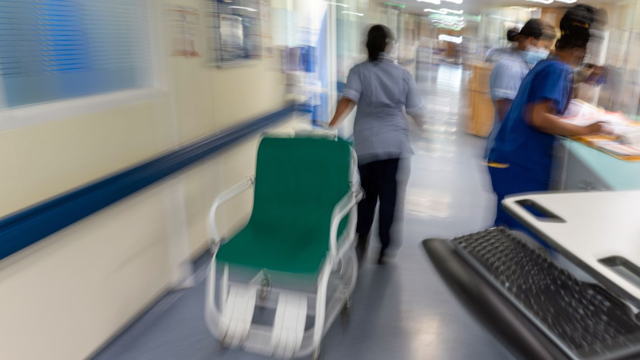 NHS staff pulling a hospital wheelchair along a corridor