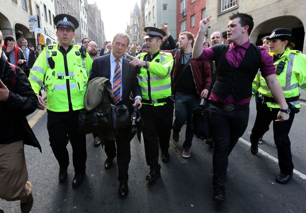 Nigel Farage (centre) is escorted by police officers as he leaves the Cannons Gait pub