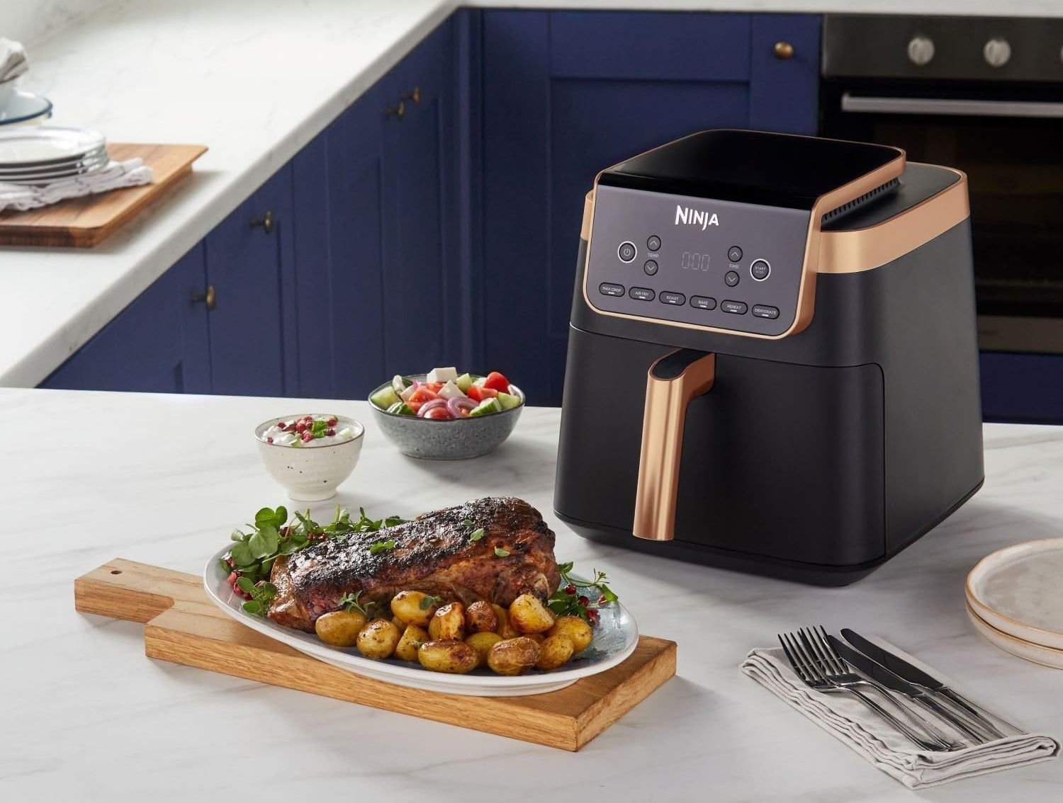 ninja air fryer in copper pictured on the kitchen sideboard surrounded by food