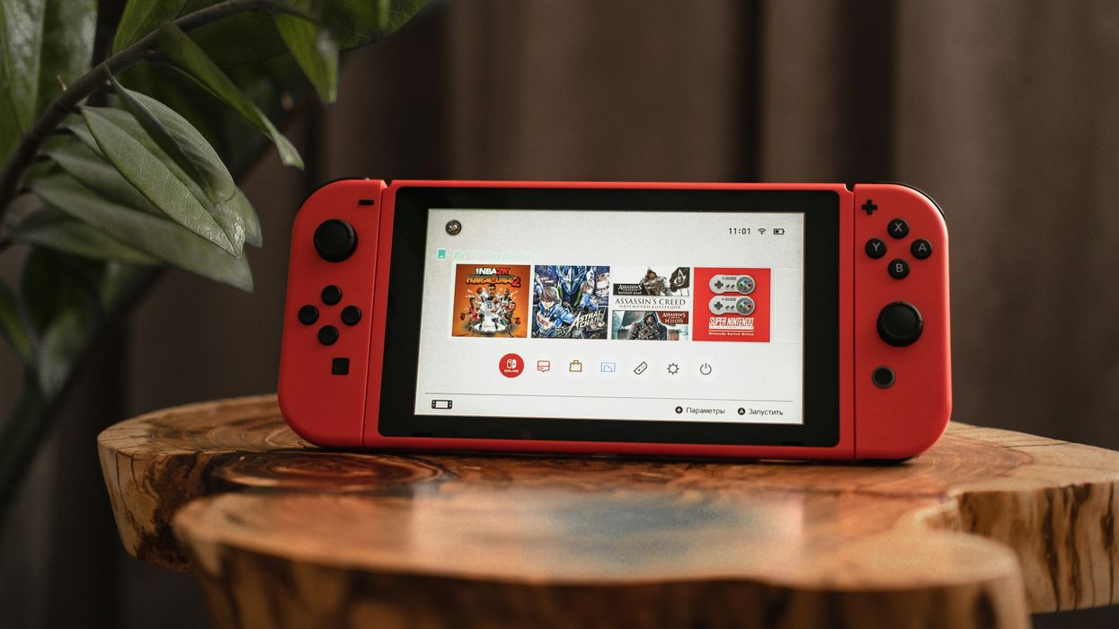 nintendo switch in red pictured on a wooden stump in a living room