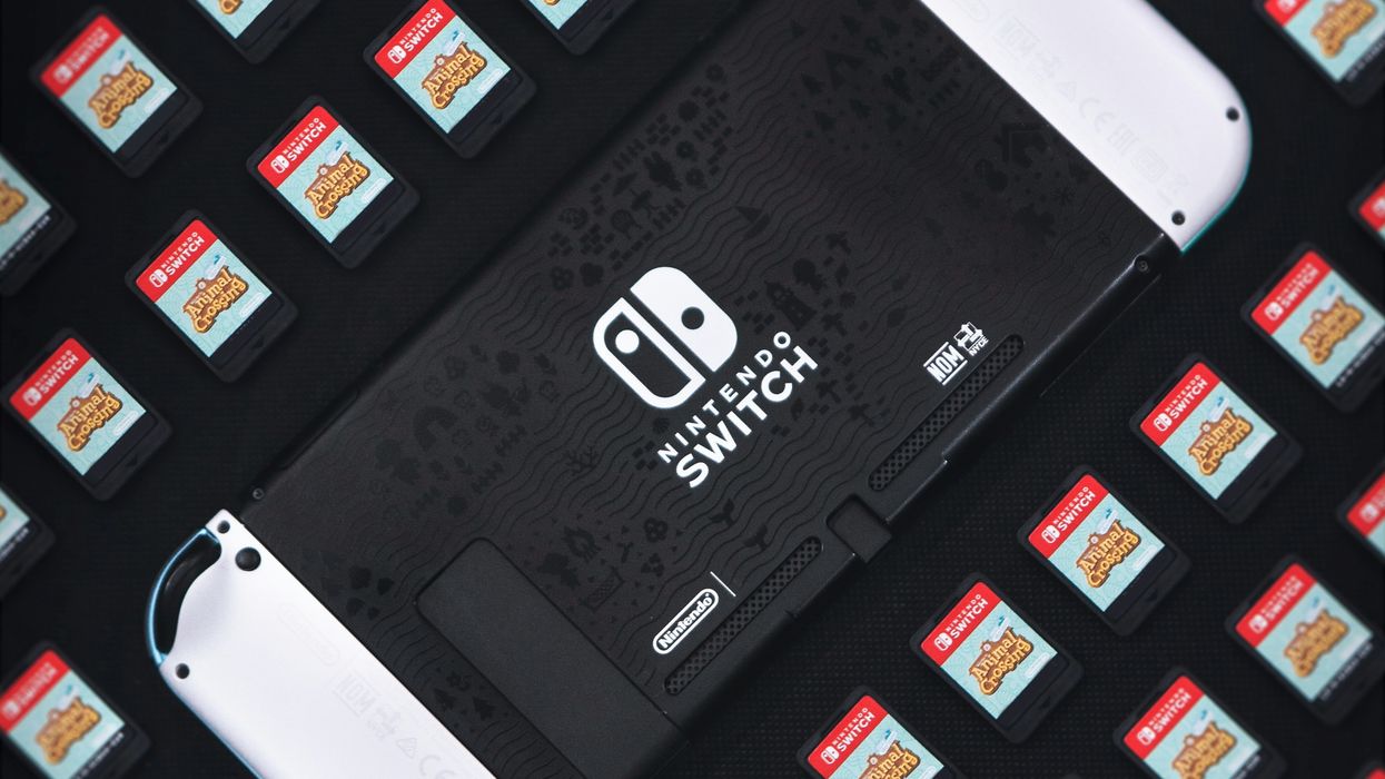 nintendo switch oled model pictured face down surround by game cartridges for the new animal crossing