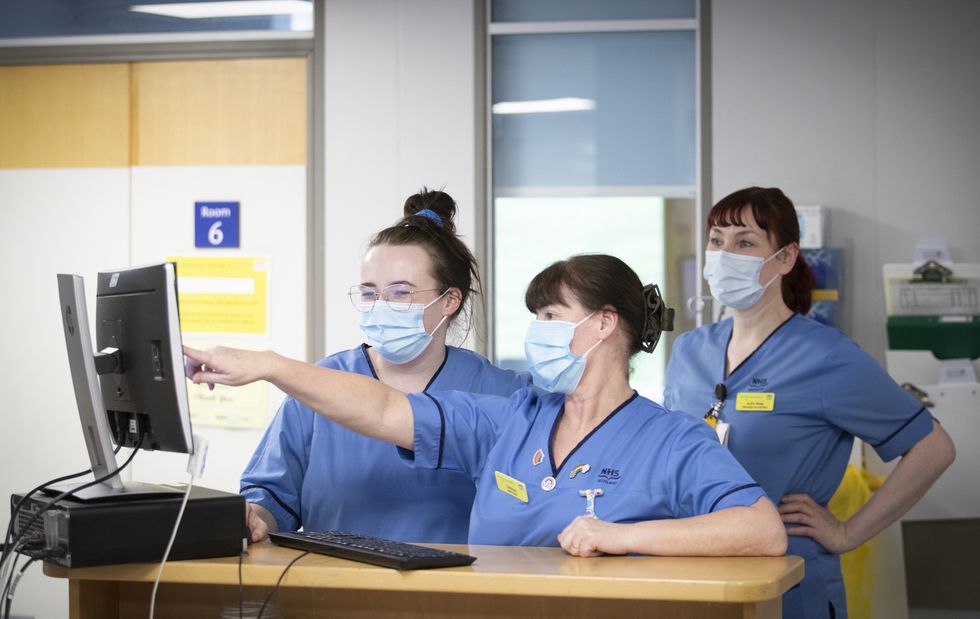 Nurses consult an NHS monitor.