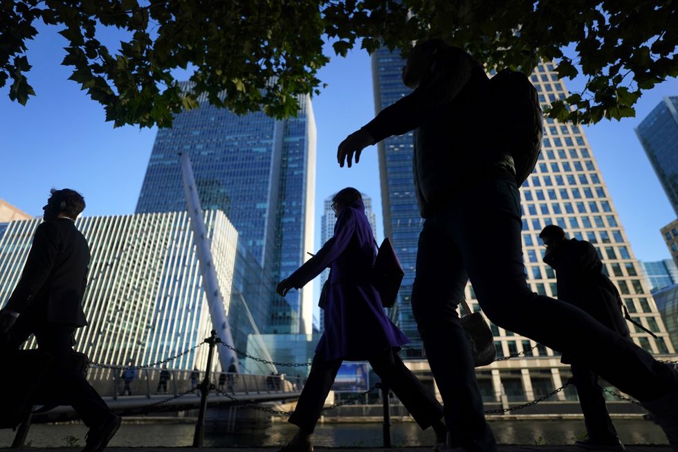 Office workers and commuters walk through Canary Wharf in London during the morning rush hour. Picture date: Wednesday October 6, 2021.