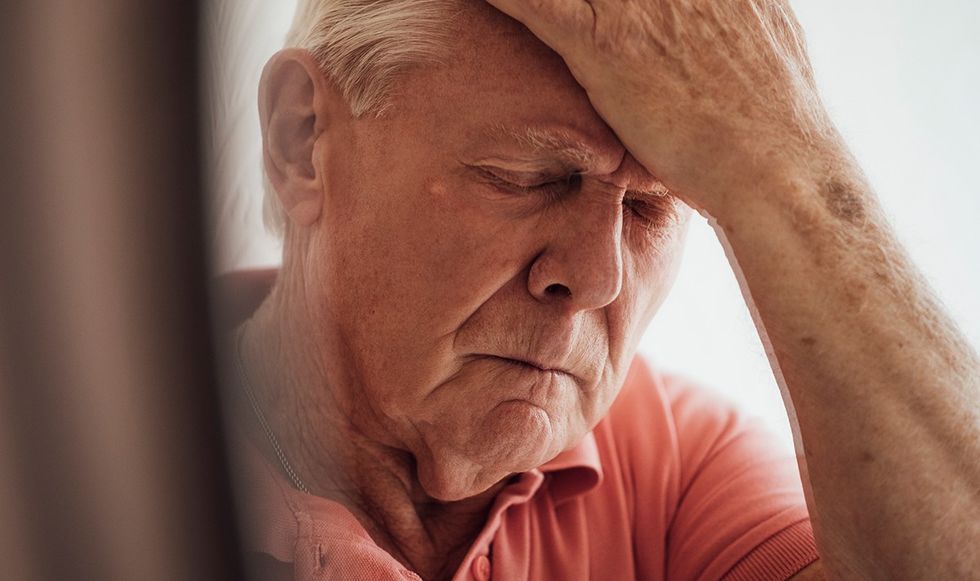 Old man gripping his head in pain