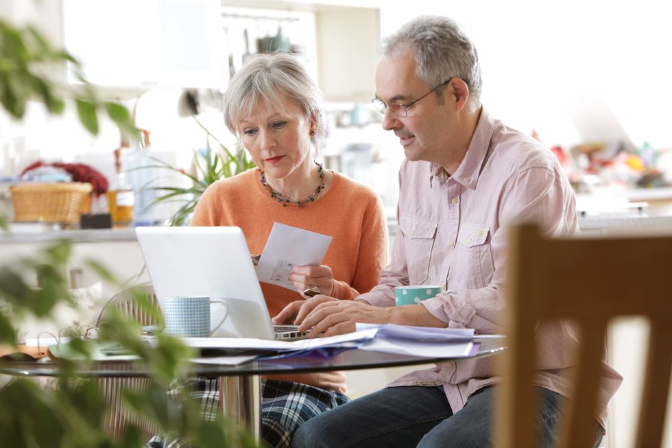 Older couple sat at home looking at laptop