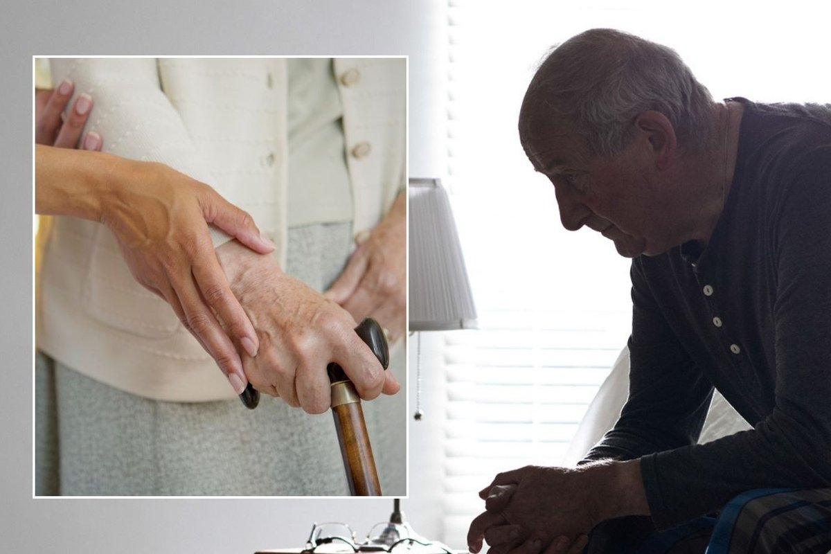 Older man looking worried and carer looking after older woman