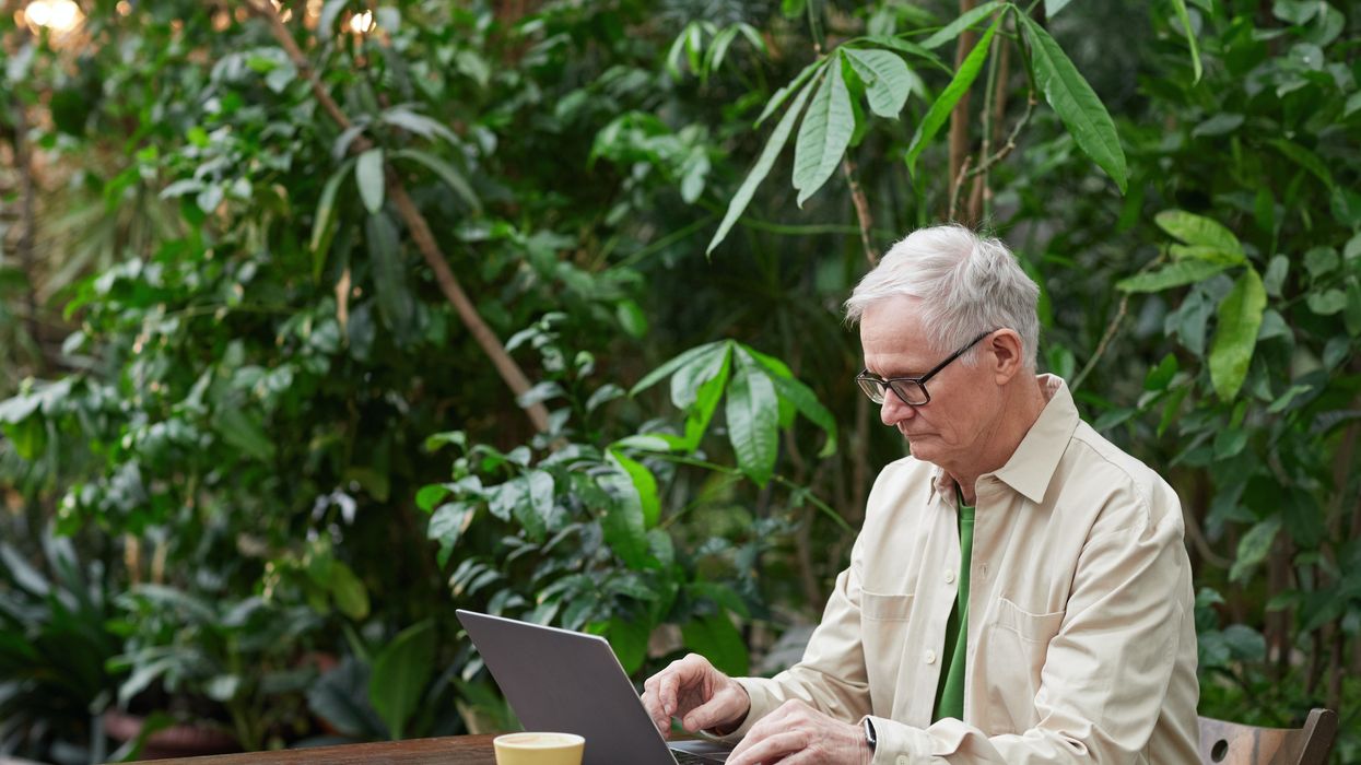 Older person looking at laptop while sitting outside in garden