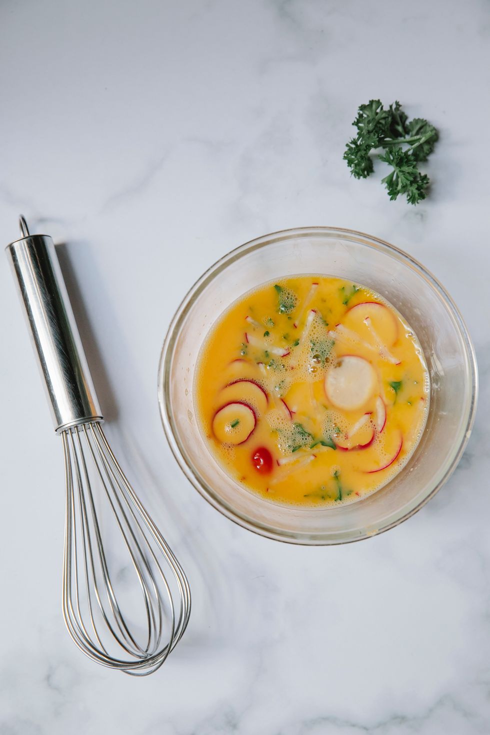 Omelette ingredients in bowl and whisk