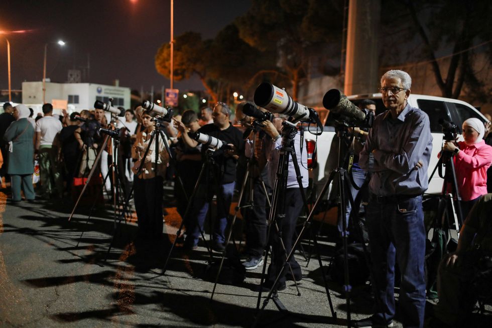 Onlookers observe the lunar eclipse through telescopes at Sports City in Amman, Jordan