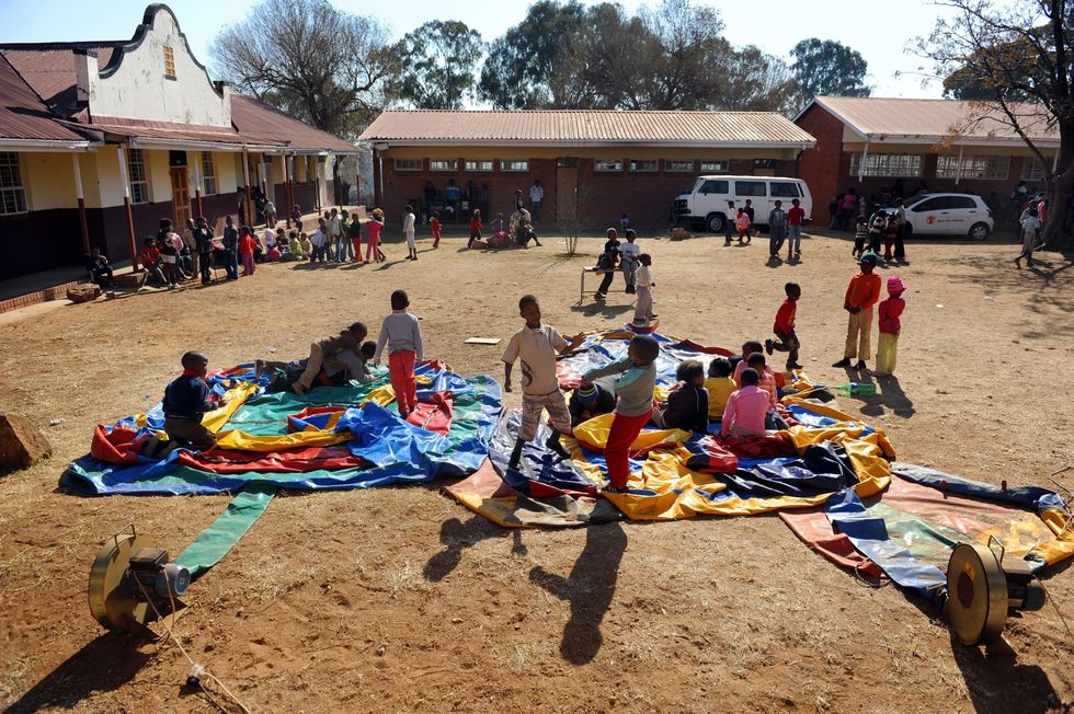 Orphaned and vulnerable children play on a deflated bouncy castle at a project run by Save The Children