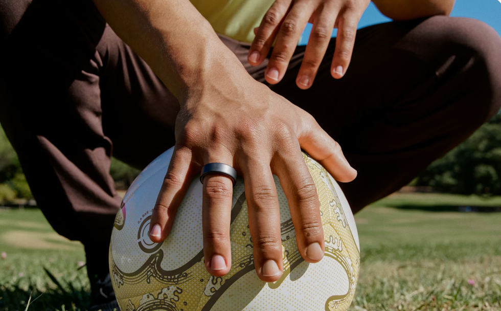 Oura Ring 4 in Stealth metallic worn on hand while playing football