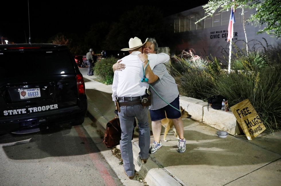 <p>A woman offering hugs and prayers embraces a Texas Ranger outside the Ssgt Willie de Leon Civic Center, where students had been transported from Robb Elementary School after a shooting, in Uvalde, Texas, US<br></p><p><br></p>