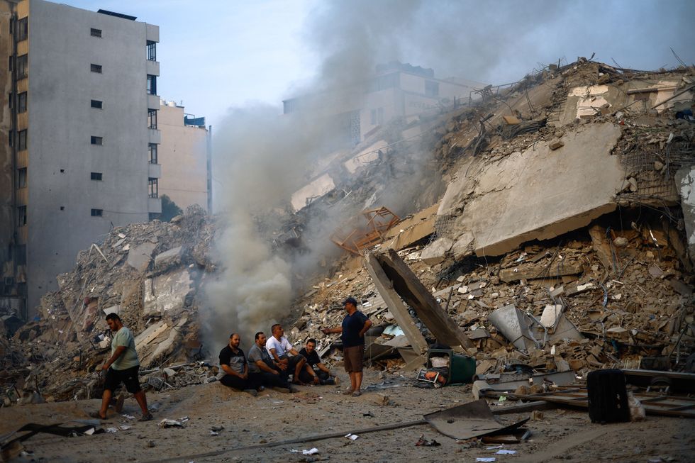 Palestinians gather next to the ruins of Watan Tower, which was destroyed in Israeli strikes