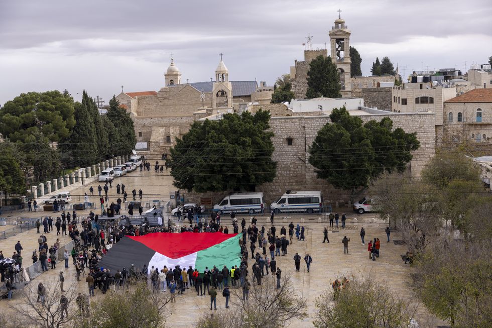 Palestinians hold a flag in the Manager Square on December 24, 2023 in Bethlehem, West Bank
