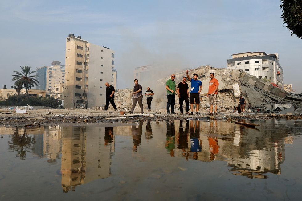 Palestinians inspect the ruins of Watan Tower, which was destroyed in Israeli strikes