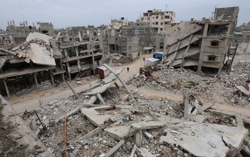 Palestinians walk surrounded by the rubble of houses destroyed in Israeli strikes during the war
