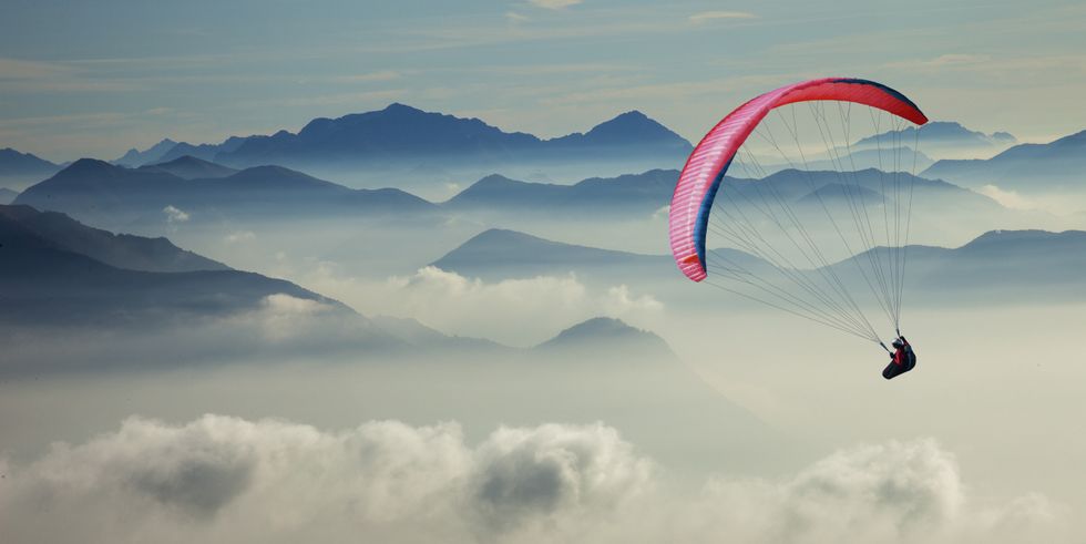 Paraglider above the clouds and mountain peaks
