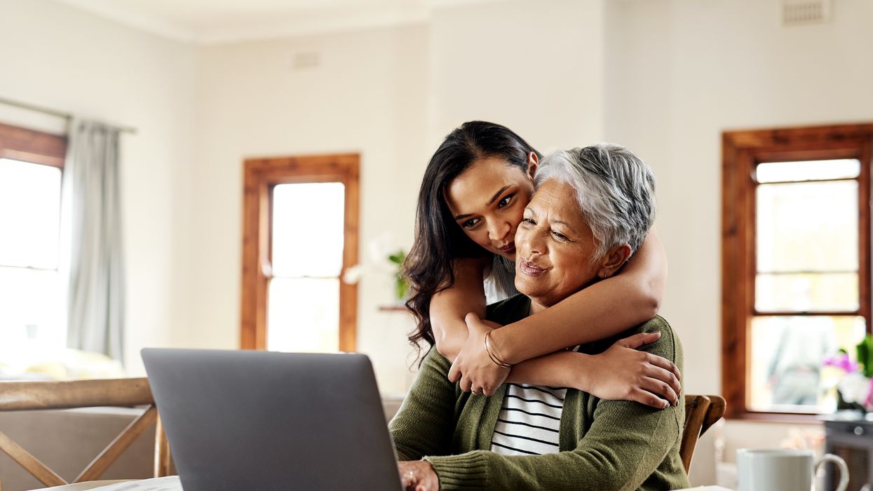 Parent and adult child hug as they look at laptop