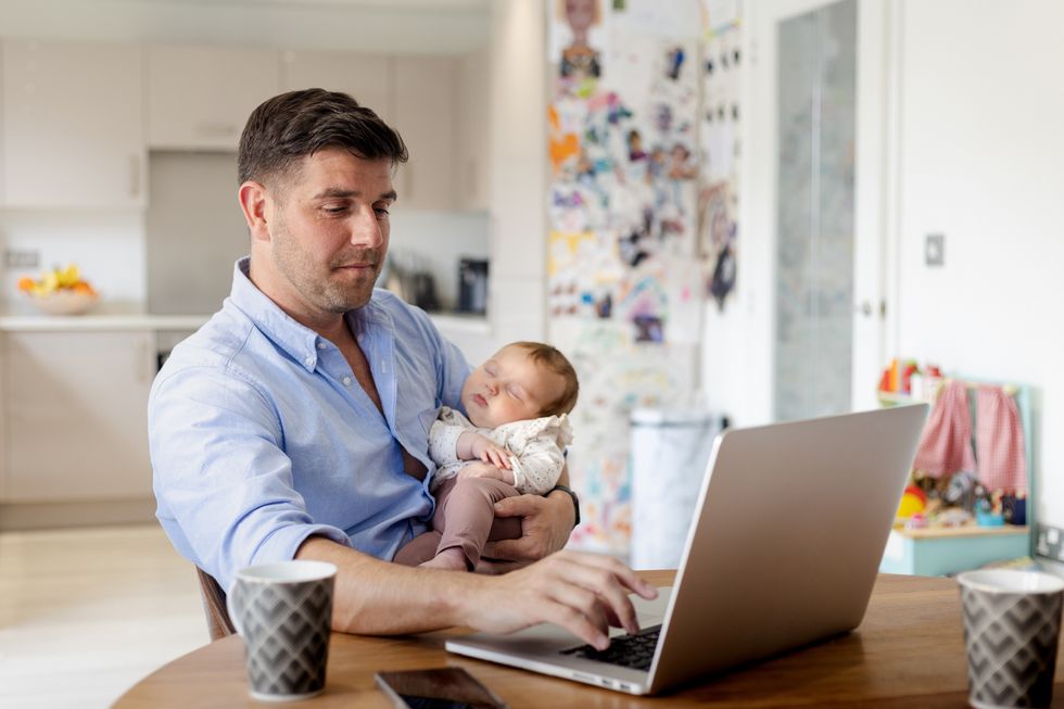 Parent holding child and looking at laptop