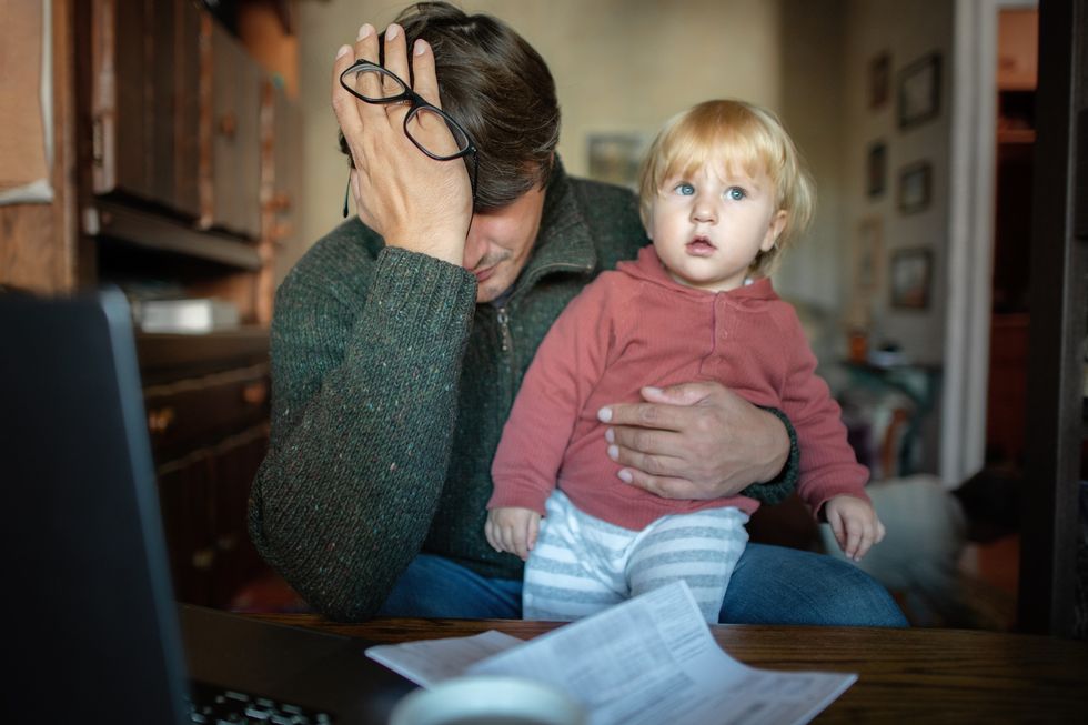 Parent looking worried at bill while holding baby