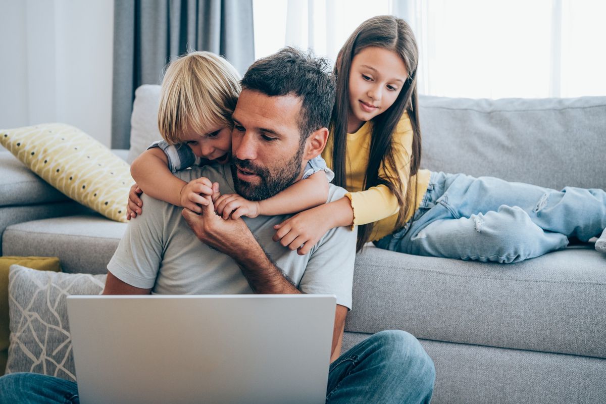 Parent trying to work from home with two children beside him 
