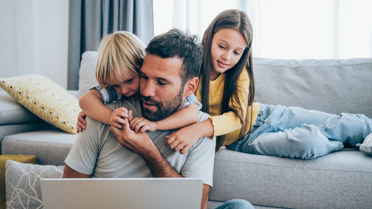 Parent trying to work from home with two children beside him