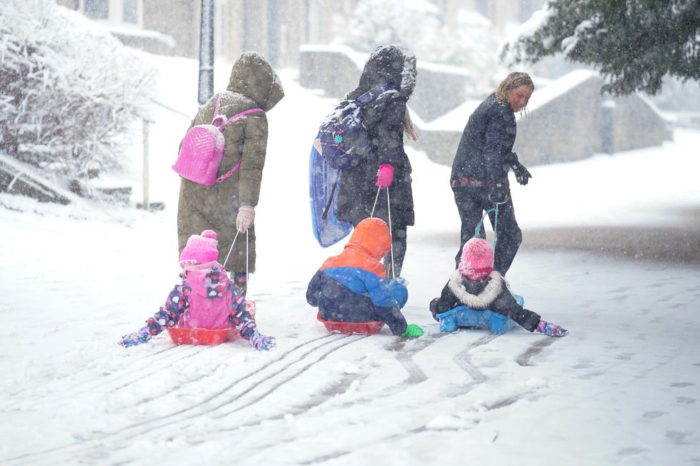 Parents pulling children along on sleighs