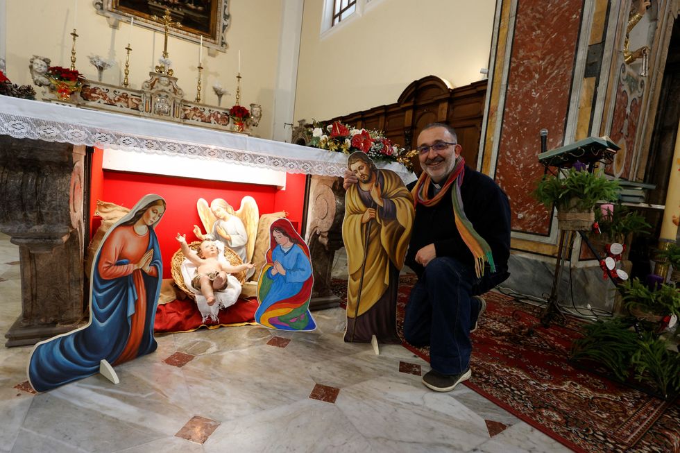 Parish priest of the Church of Saints Peter and Paul, Vitaliano Della Sala poses for a photo in front of a nativity scene featuring two mothers of the Baby Jesus