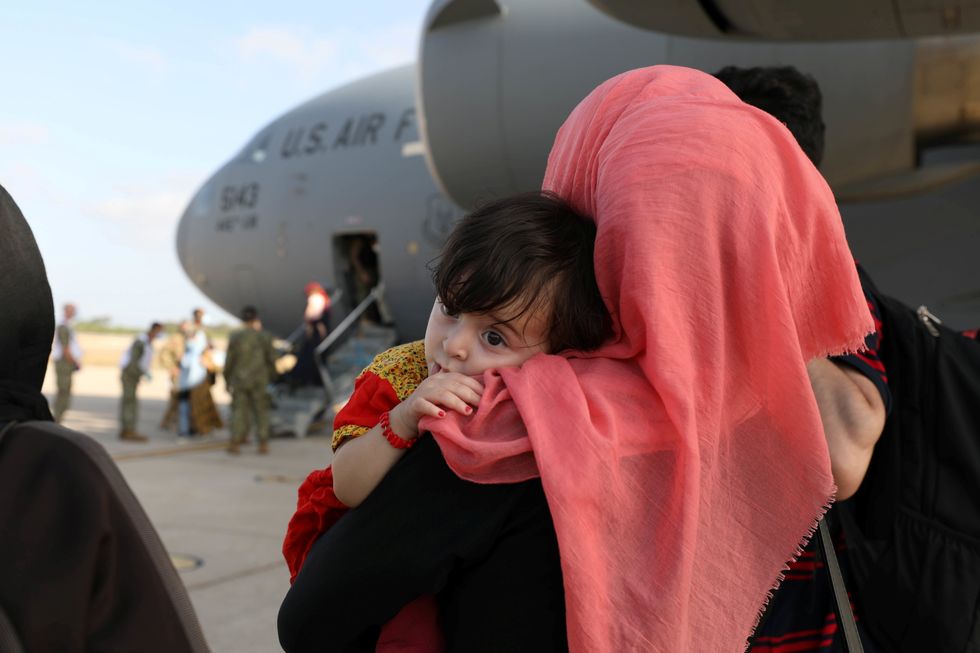 Part of group of 450 Afghan citizens who have been evacuated from Kabul watch as other compatriots leave a U.S. Air Force C-17 Globemaster III transport plane after arriving from Kuwait, at Naval Station (NAVSTA) Rota Air Base in Rota, southern Spain, August 27, 2021.