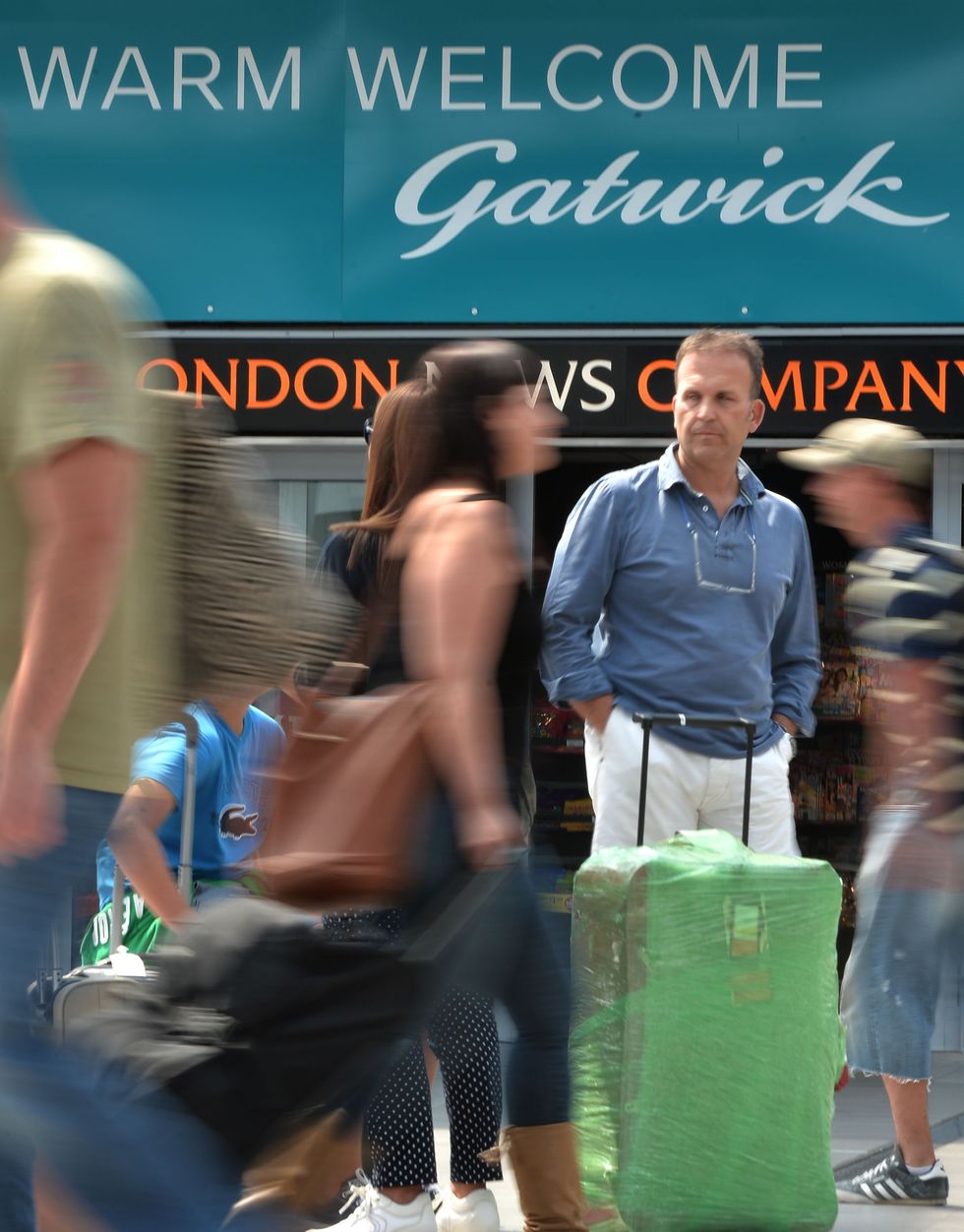 Passengers in front of a Gatwick sign