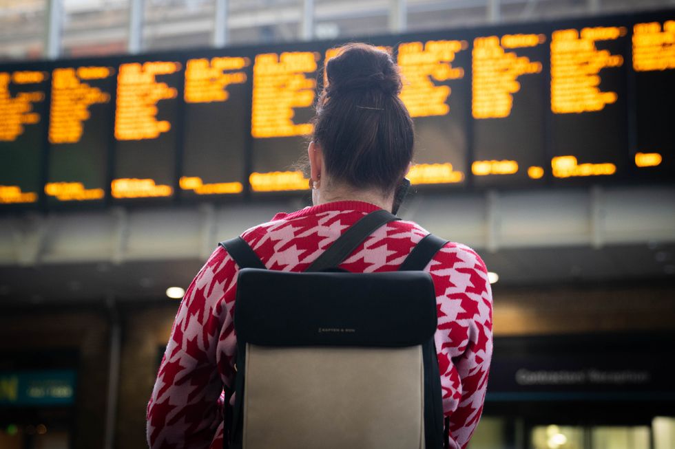 Passengers look at the departure board at Kings Cross station in London