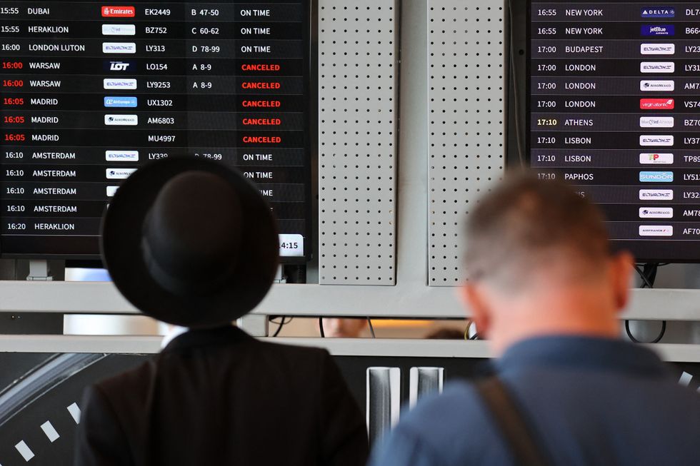 Passengers look at the flight board at Ben Gurion airport near Tel Aviv