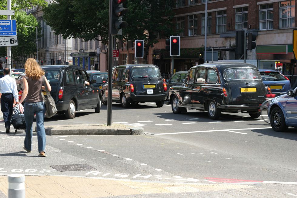 Pedestrians crossing a busy road with cars