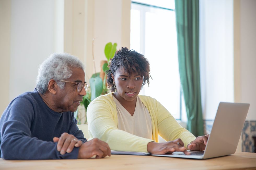 Pensioner and younger person on laptop