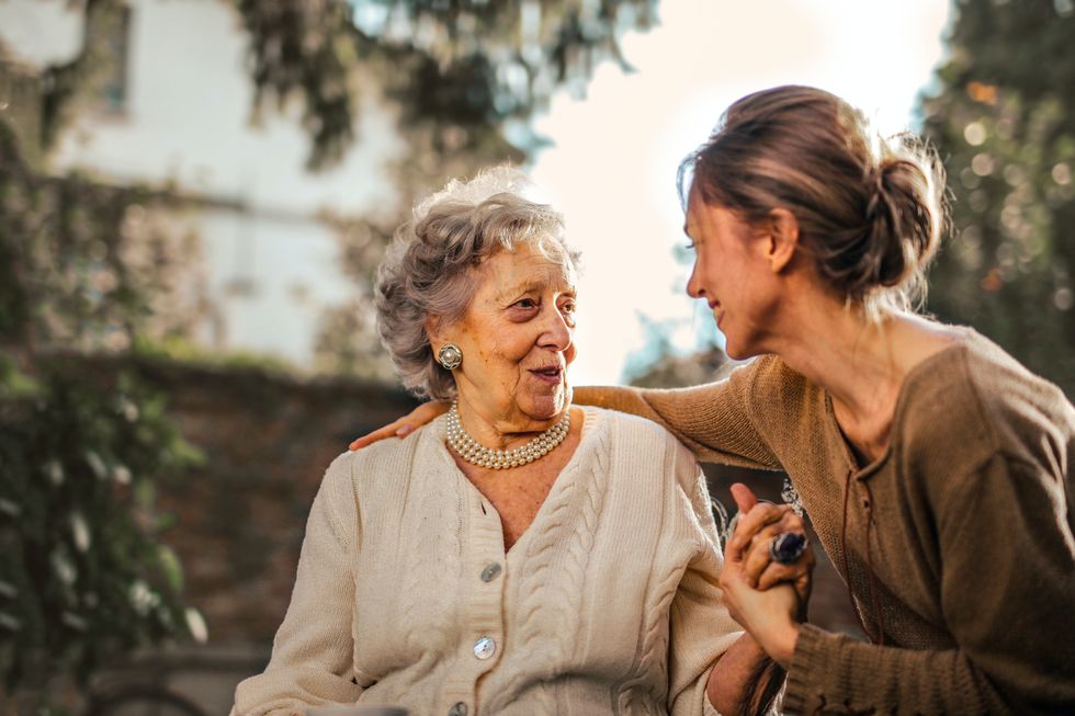 Pensioner and younger person sit outside together