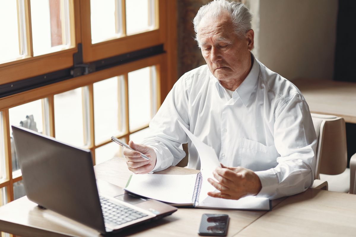 Pensioner looking at finances with laptop in front of him
