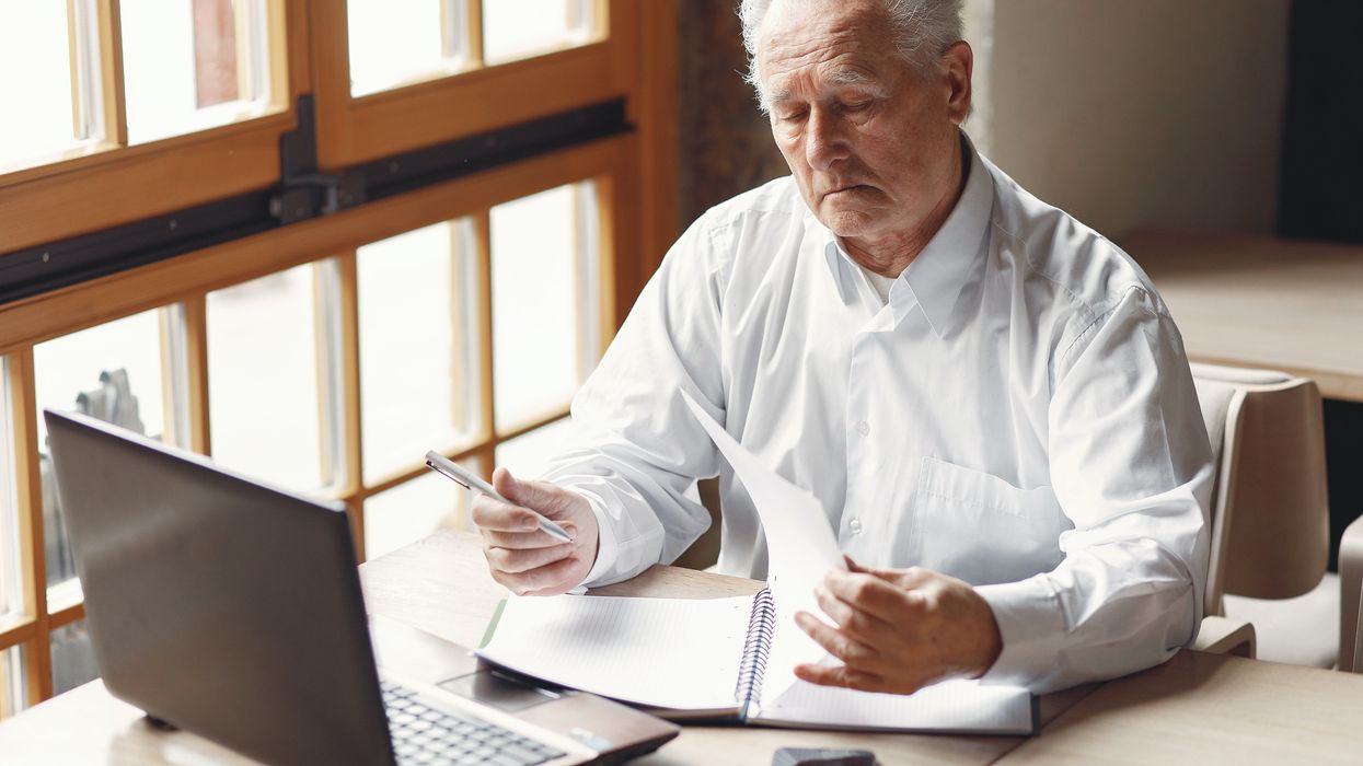 Pensioner looking at finances with laptop in front of him