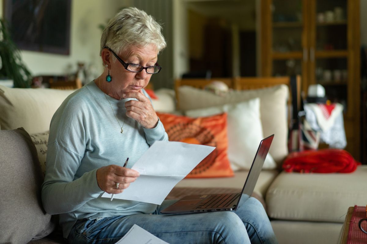 Pensioner looks at bank statement and laptop
