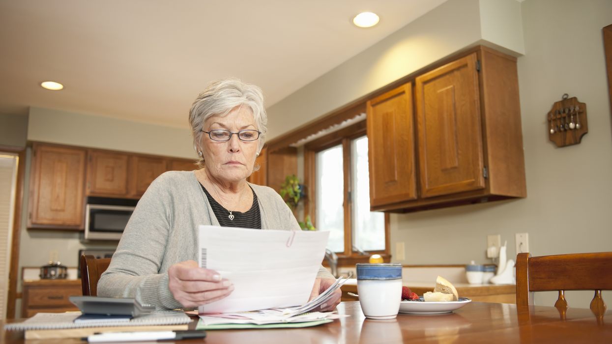 Pensioner looks at bank statements at kitchen table