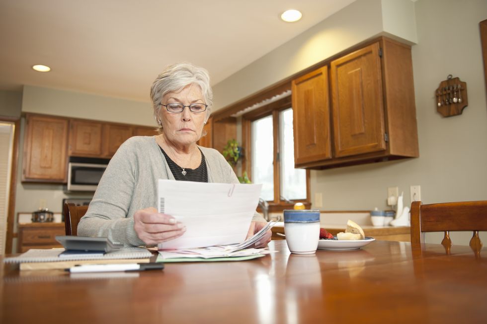 Pensioner looks at bank statements at kitchen table
