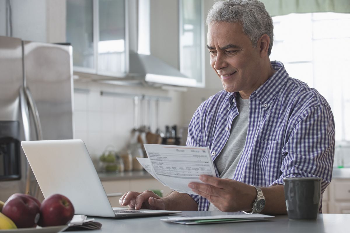 Pensioner looks at laptop and financial documents 